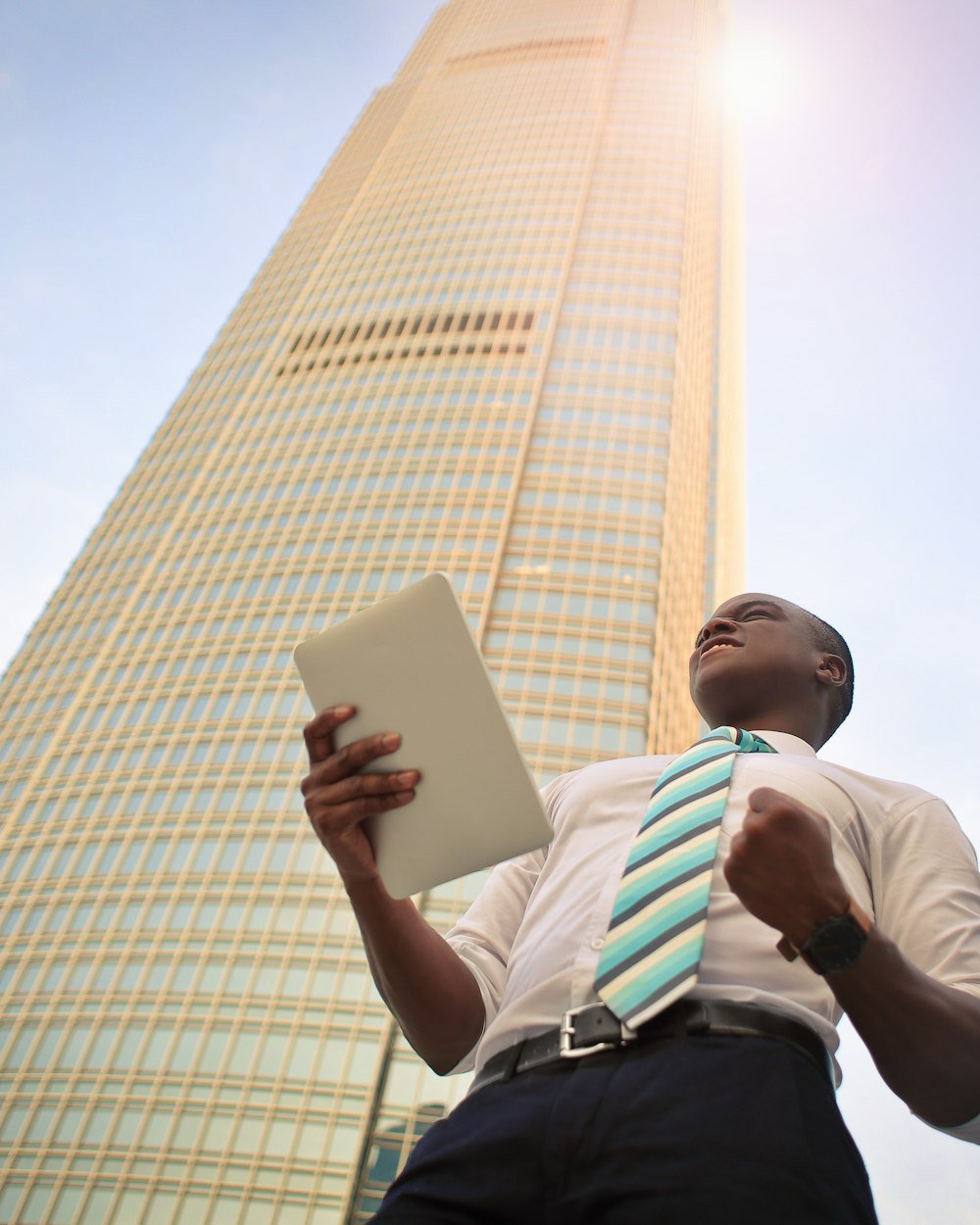 Professional looking up at a glass tower while holding a tablet