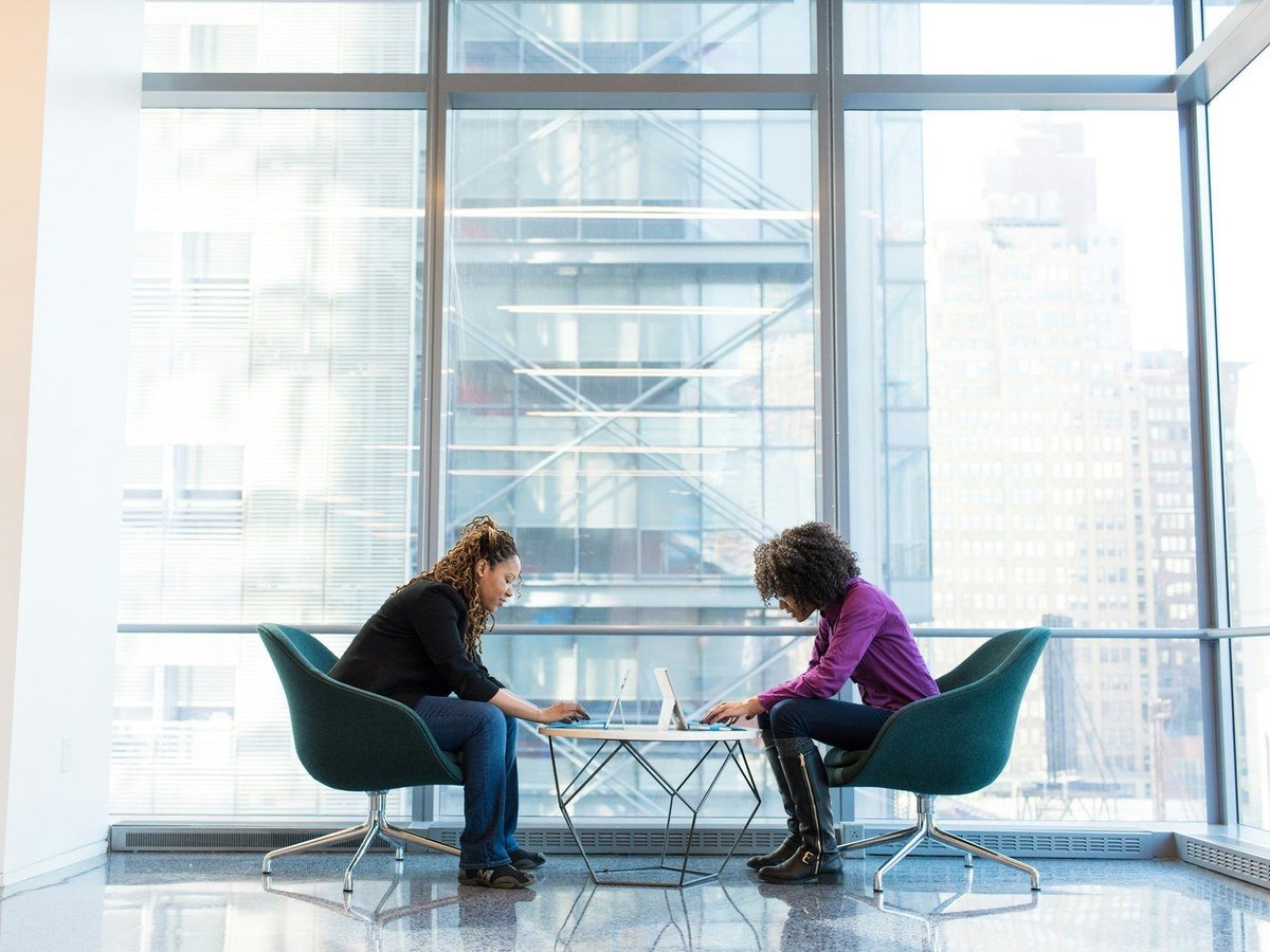 Two colleagues working at a table beside a window